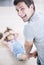 Rear view portrait of happy father dragging daughter on floor at home