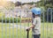 Rear view portrait ofSad little boy looking through metal fence , Lonely kid playing scooter alone in playground, Portrait Child