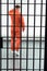 rear view of prisoner in prison cell with metallic bars