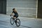 Rear view of professional female cyclist in black cycling garment and protective gear riding bicycle in city, passing