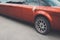 A rear view of a red long limousine with a decoration on the back door handle. The rear part of a festive red limousine