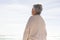 Rear view of retired biracial senior woman looking at sea against sky from beach on sunny day