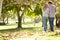 Rear View Of Romantic Couple Walking Through Autumn Woodland