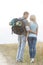 Rear view of romantic hiking couple looking at each other while standing at field