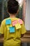 Rear view schoolboy with paper for notes glued on yellow t-shirt with inscriptions: Smart Motivation Knowledge Education