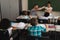 Rear view of schoolkids studying and sitting at desk in classroom