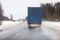Rear view at semitrailer truck driving on slippery winter road in northern forests