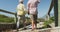 Rear view of senior caucasian couple holding hands and walking on path leading to the beach