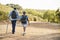 Rear View Of Senior Couple Wearing Backpacks Hiking In Countryside Together