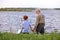 Rear View On Senior Grandfather And Grandson Going To Fish On Riverside in Countryside