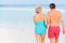 Rear View Of Senior Romantic Couple Walking In Tropical Sea