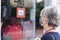 Rear view of senior woman grey-haired looking at the window shop with products on special offer