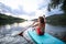 Rear view of senior woman paddleboarding on lake in summer.