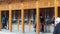 Rear view of Several tibetan pilgrims are walking and turning huge and colorful prayer wheels in the Labrang monastery in Xiahe