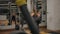 Rear view of sexy caucasian woman trainer doing barbell squats indoor of gym