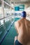 Rear view of shirtless swimmer by pool at leisure center