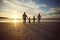 Rear view shot of a carefree family holding hands while walking on the beach at sunset against cloudy sky. Loving