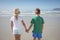 Rear view of siblings holding hands on shore at beach