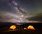 Rear view silhouette of four people sitting beside camp in night under sky with many stars