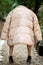 Rear view on small woman dwarf dressed in beige jacket