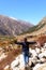 Rear View of Solo Woman Indian traveler in winter casual standing alone with arms outstretched in remote mountain valley. Snow