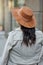 Rear view of a stylish woman wearing grey coat and hat standing on the city street, walking on warm autumn day