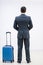 Rear view of successful businessman in suit standing in airport terminal, with suitcase over white background.