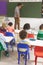 Rear view of teacher writting on greenboard with a piece of chalk