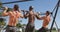 Rear view of three diverse shirtless fit men exercising outside, doing chin-ups on a climbing frame