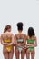 Rear view of three female models with different body types in colorful underwear holding hands, supporting each other