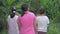 Rear view of three Thai teen girls in casual dress walking leisurely among the natural field in the countryside in the morning.