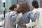 Rear view of three women standing on a street..