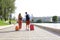 Rear view of tourist couple holding hands and dragging luggage, sightseeing visiting street, outdoors