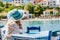 Rear view of tourist woman sitting in a cafe wear blue sunhat enjoying colorful tranquil houses of Assos village on