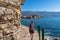 Rear view of touristic woman on Idyllic walk along steep high cliffs to the central beach Mogren of coastal tourist city of Budva