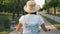 Rear view, tracking shot of woman cyclist on retro old bike in park at sunset. Young brunette girl rides bicycle on cycle path in