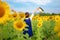 Rear view of travel lifestyle women with hands up hat in sunflower field, in summer day and happy vocations.