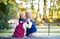 Rear view of twin toddler sibling boy and girl sitting in autumn forest.