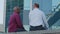 Rear view of two elderly men friends old colleagues or successful mature businessmen sitting outdoors in city discussing
