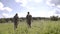 Rear view of two men walking with fishing poles in field to river. Relaxed men spending leisure together and going for