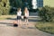 Rear view of two schoolgirl girlfriends elementary school students walking with school bag in the yard