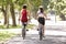 Rear View Of Two Women Cycling Through Park