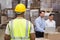 Rear view of warehouse worker in front of his managers