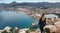 Rear view woman climbed up on peak of Penon de Ifach rock enjoy picturesque view Mediterranean Sea, mountain range, cityscape