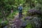 Rear view of woman engaged in nordic walking on rocky path.