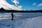 Rear view of woman with hiking backpack watching the frozen lake Forstsee, Techelsberg, Carinthia (Kaernten), Austria,