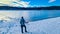 Rear view of woman with hiking backpack watching the frozen lake Forstsee, Techelsberg, Carinthia (Kaernten), Austria,