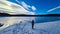 Rear view of woman with hiking backpack watching the frozen lake Forstsee, Techelsberg, Carinthia (Kaernten), Austria,