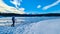 Rear view of woman with hiking backpack watching the frozen lake Forstsee, Techelsberg, Carinthia (Kaernten), Austria,