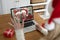 Rear view of woman in santa hat waving while having a videocall with senior couple in santa hats on